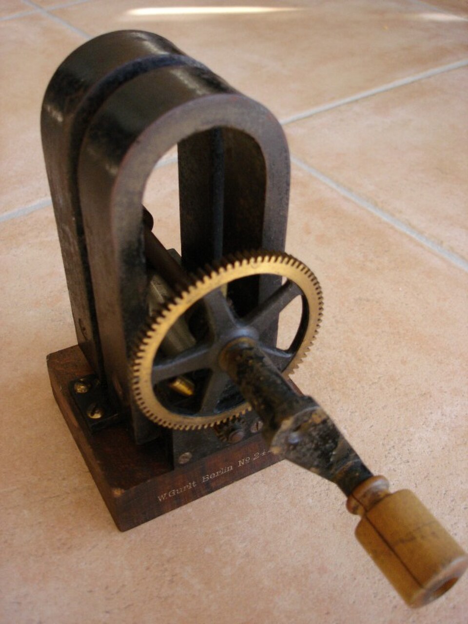 Hand-cranked AC generator (W. Gurlt, telephone magneto): wound armature rotating between the poles of two horseshoe permanent magnets — classic demonstration of induction.